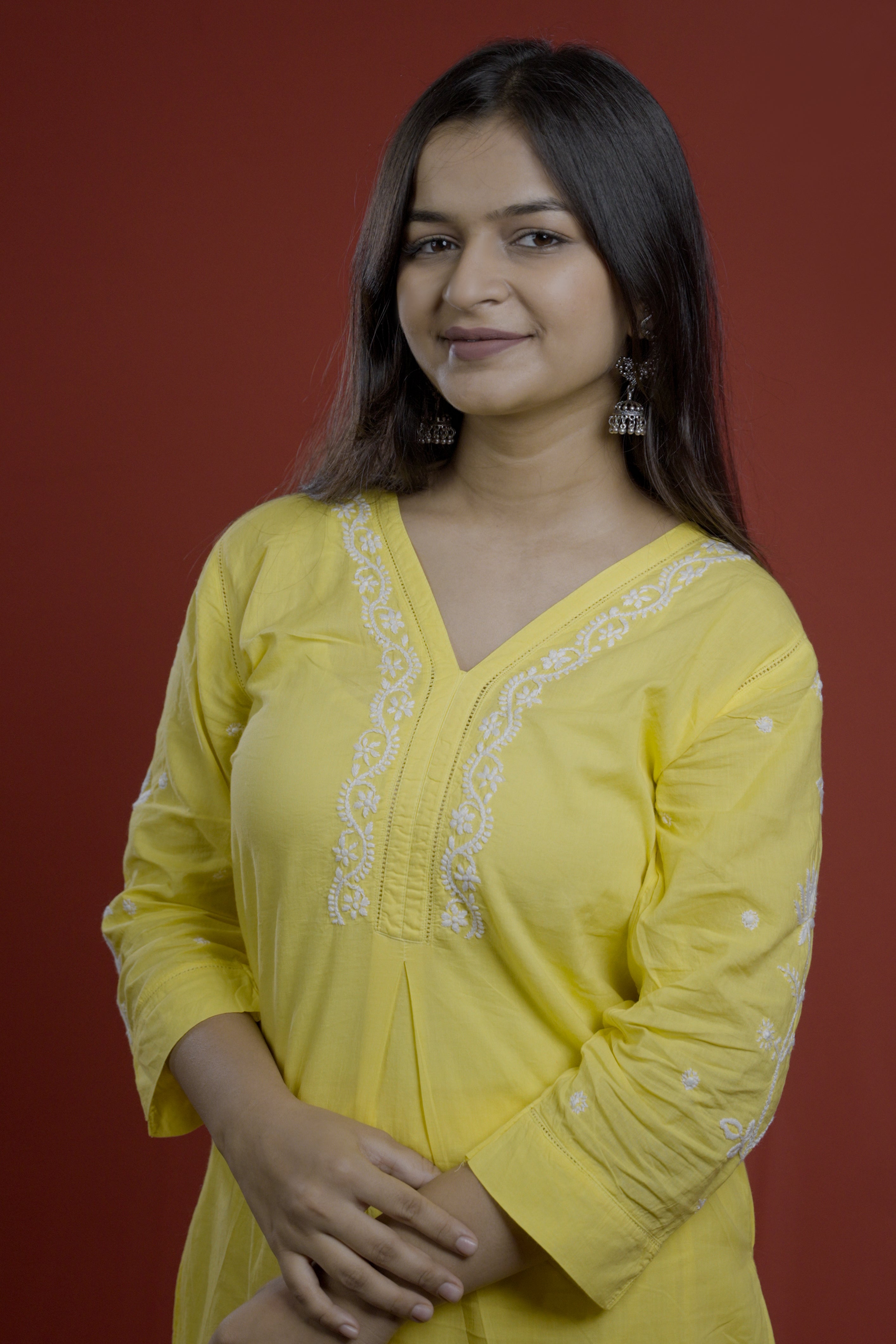 Woman wearing a yellow embroidered top of zurrii against a red background