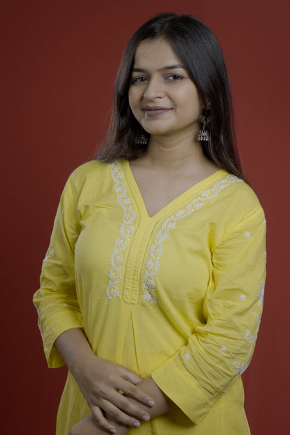 Woman wearing a yellow embroidered top of zurrii against a red background