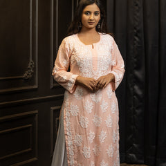Woman wearing a light pink and white traditional outfit with a dark background