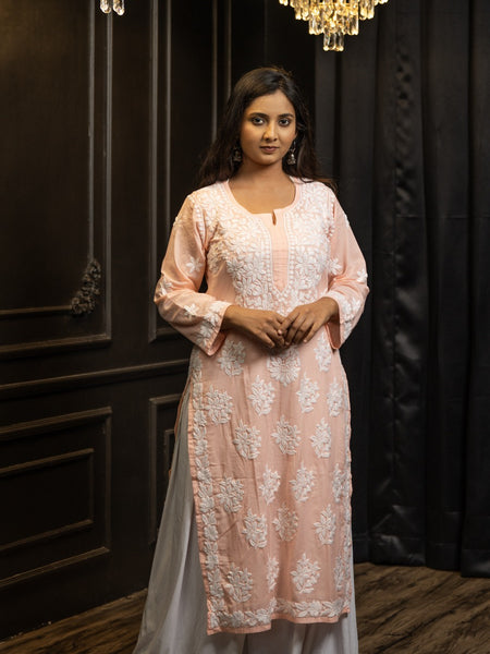 Woman wearing a light pink and white traditional outfit with a dark background